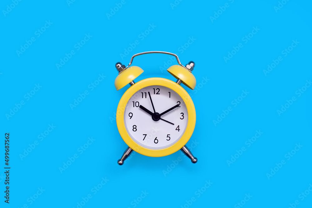 Yellow old-fashioned alarm clock with a dial on a blue background with free space for text. The concept of punctuality or routine. Vintage alarm clock from the past Yellow old-fashioned alarm clock with a dial on a blue background with free space for text. The concept of punctuality or routine. Vintage alarm clock from the past
