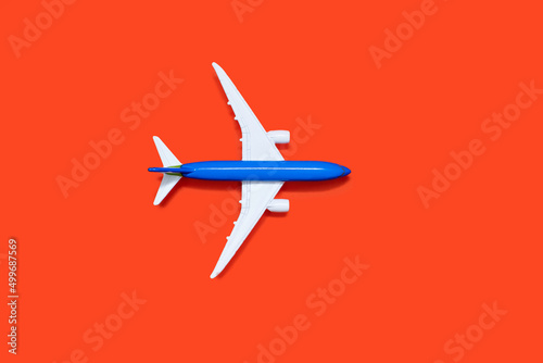 Model of a blue-white aircraft on an orange background. Tourism or freight transport concept. Top view toy airplane on orange background