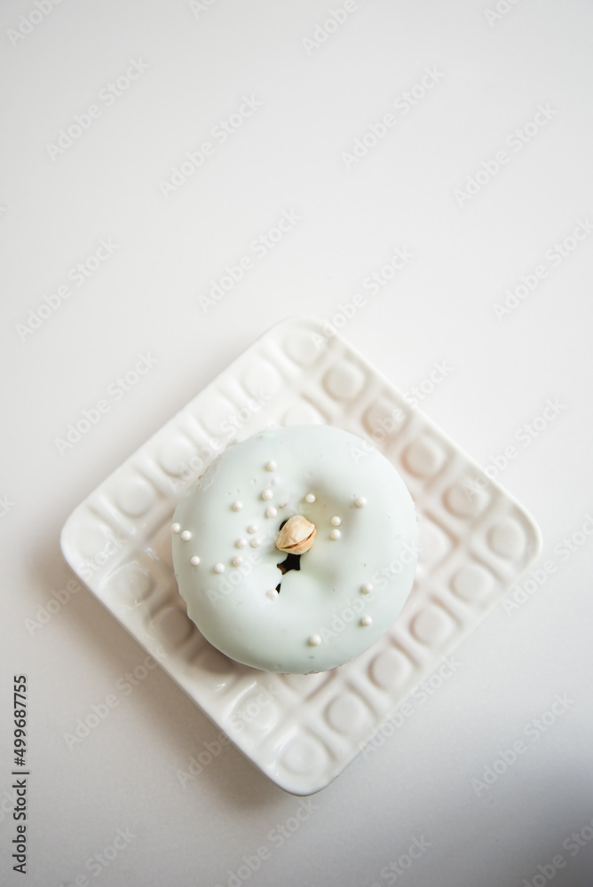 A frosted pastel pistachio cake donut on a white plate A frosted pastel pistachio cake donut on a white plate