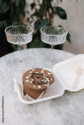 Chocolate bento cake with white candle and chmpagne glasses on luxury marble table photo