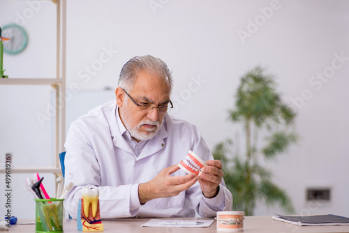 Old male dentist working in the clinic photo