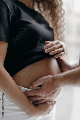 Pregnant woman and her husband holding hand together on belly. Pregnancy