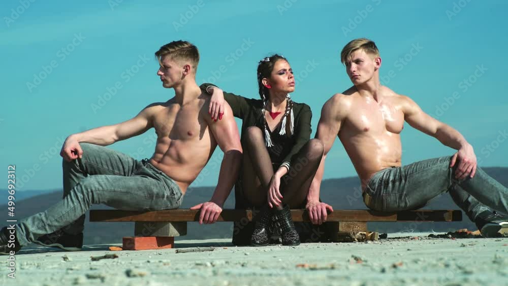 Youth festival. Group of fashion youth. Two naked bare torso muscle men and charisma charm glamor girl posing outdoor. Hippie fashion girl. Youth culture, style and fashion. Urban culture concept.