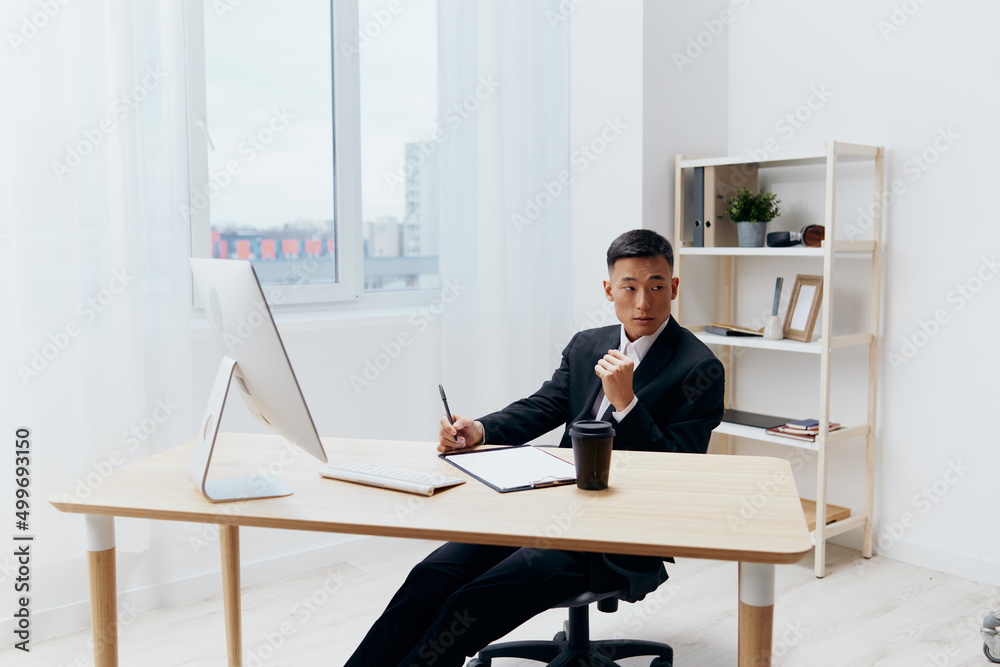 manager in a suit glass of coffee sits at a tablein front of a computer Workspace