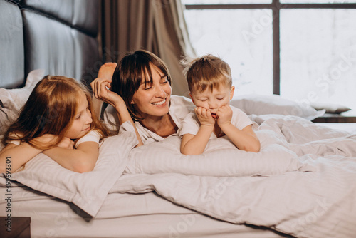 Mother with son and daughter having fun in bed