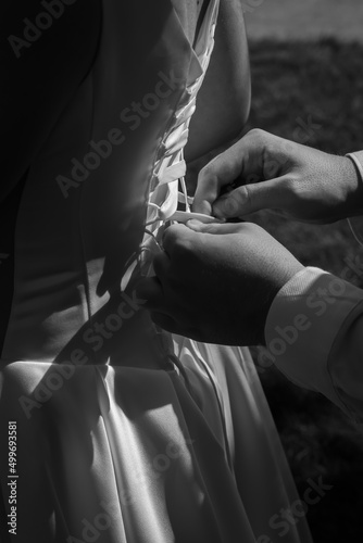 Tying a corset close-up of the hand. Back of the bride, white dress, black and white