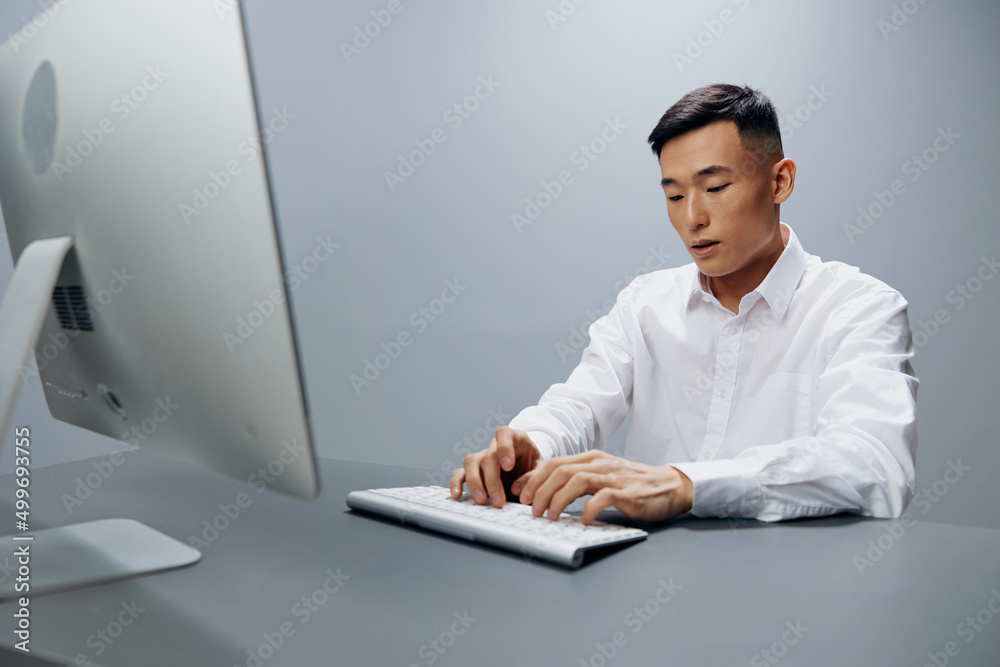 businessmen in a white shirt works at a computer in the office Gray background