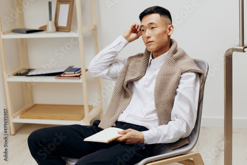Asian man with a tablet sits in a chair communication Lifestyle