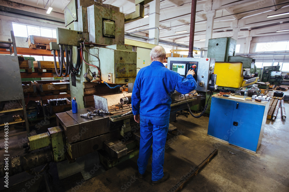 Factory engineer adjusting operation parameters of CNC lathe machine