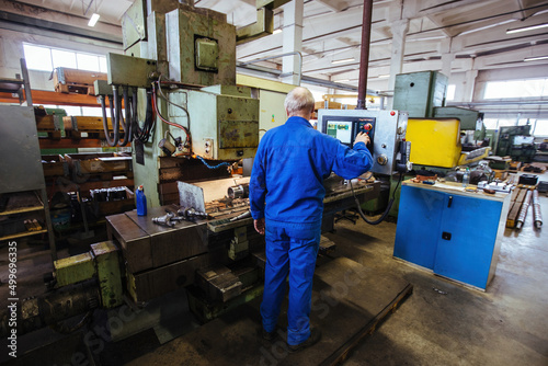 Factory engineer adjusting operation parameters of CNC lathe machine