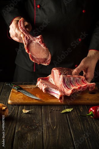 The cook is holding a piece of raw meat with a bone. Pork ribs in the butcher hands. Asian cuisine.