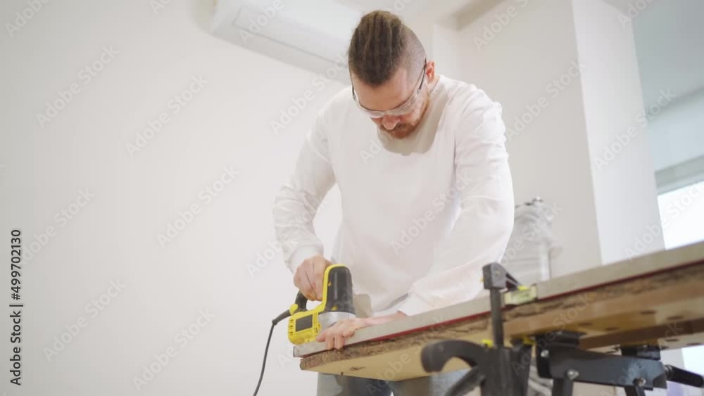 carpenter in protective glasses cuts wood with electric jigsaw carpenter in protective glasses cuts wood with electric jigsaw