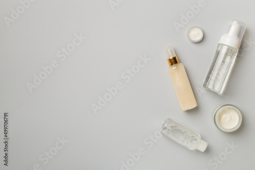 Different cosmetic bottles on color background, top view