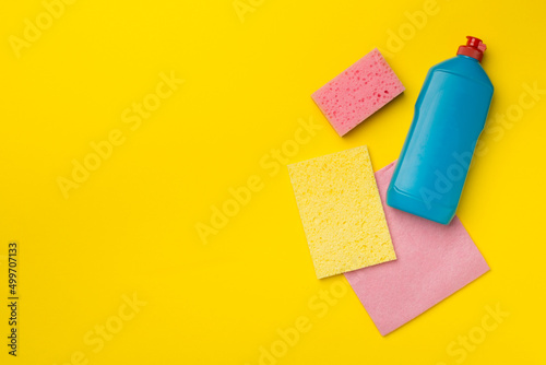Bottle with dishwashing detergent and sponges on color background, top view