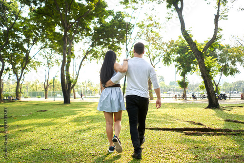Mulethnic couple walking in an urban park holding each other's backs