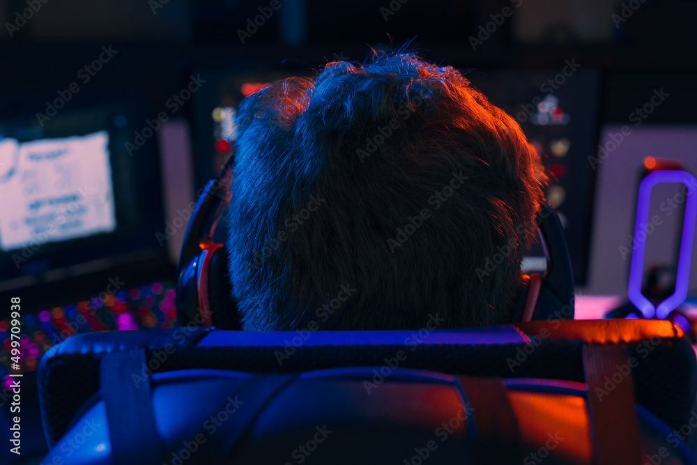 Φωτογραφία Silhouette of the back of a young man addicted to video games playing on a computer with headphones