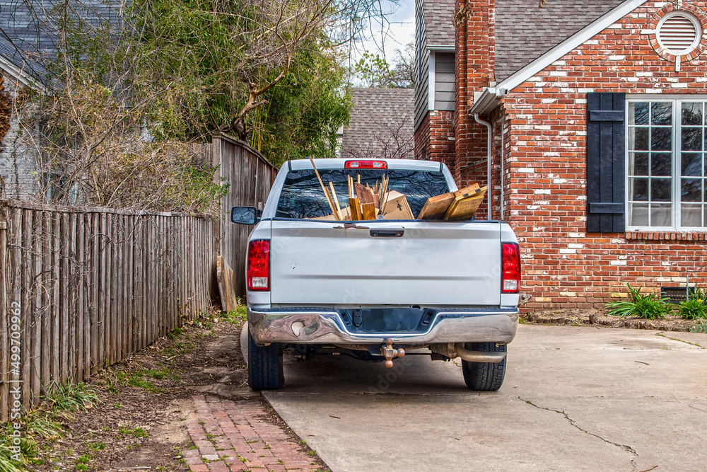 Foto White pickup truck full of trash-boards and boxes- parked in driveway of brick h