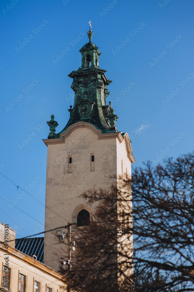 Tower of the Latin Cathedral of the Assumption of the Blessed Virgin in Lviv with a tree in the foreground. The historical part of the city, view from below against the blue sky.