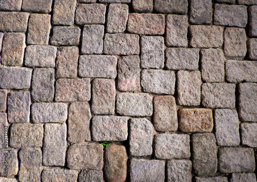 Granite cobblestoned pavement background. Stone pavement texture. Abstract background of cobblestone pavement close-up.