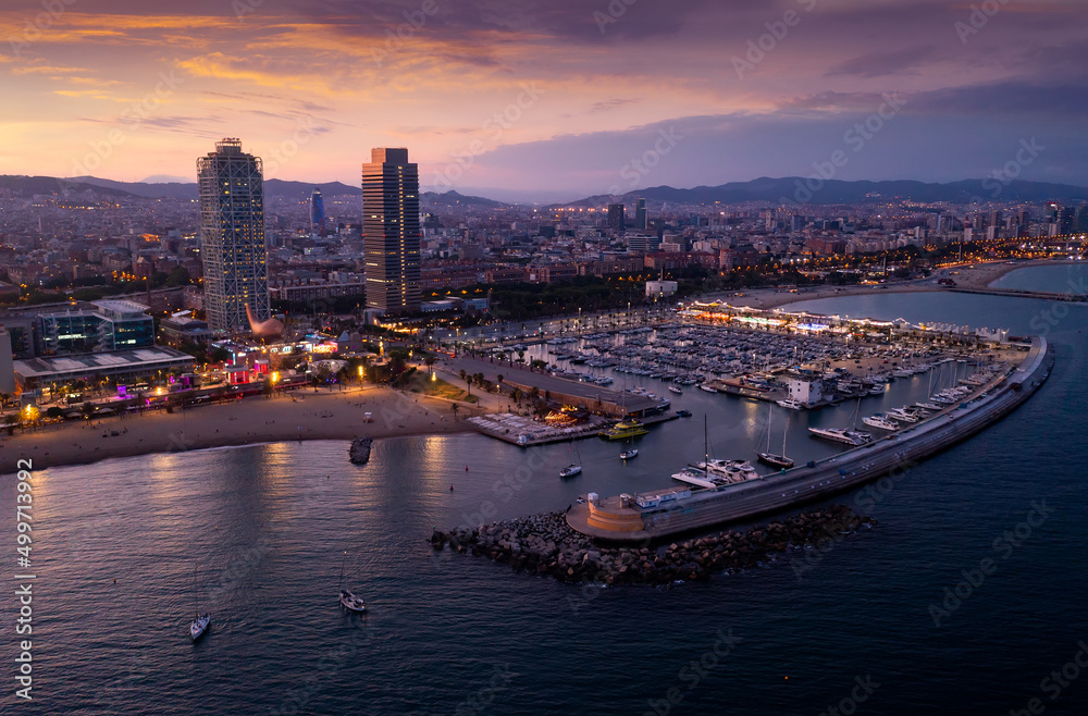Aerial view of seaside area of Barcelona overlooking two modern skyscrapers on Mediterranean coast and marina for pleasure yachts in summer dusk, Spain