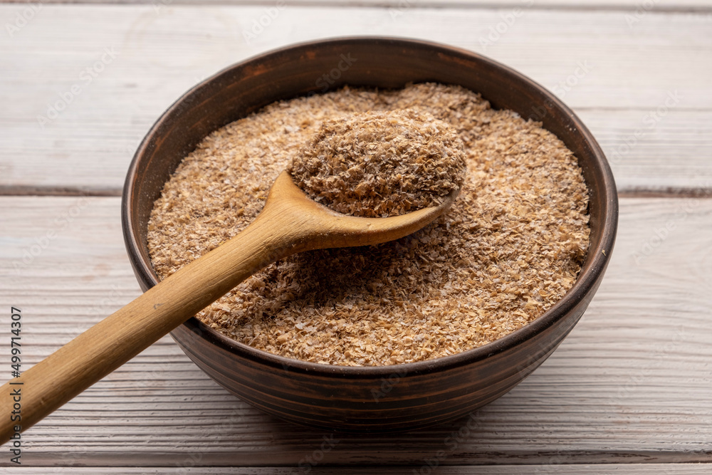 Wheat bran in bowl on a white wooden table. Wheat bran in bowl on a white wooden table.