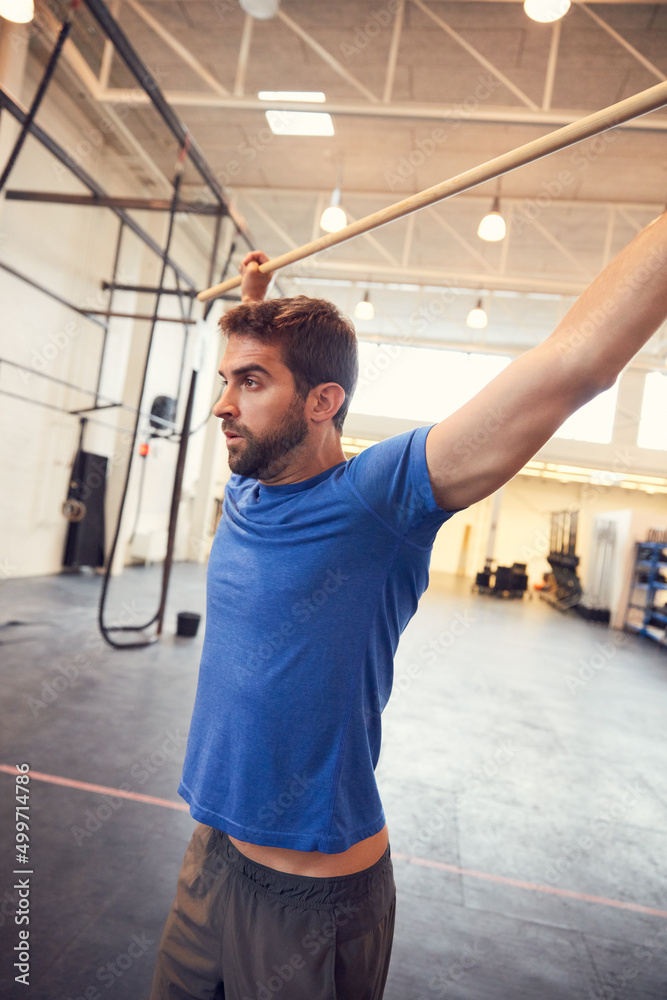 You earn your body. Cropped shot of a handsome young man working out with a stick in the gym. You earn your body. Cropped shot of a handsome young man working out with a stick in the gym.