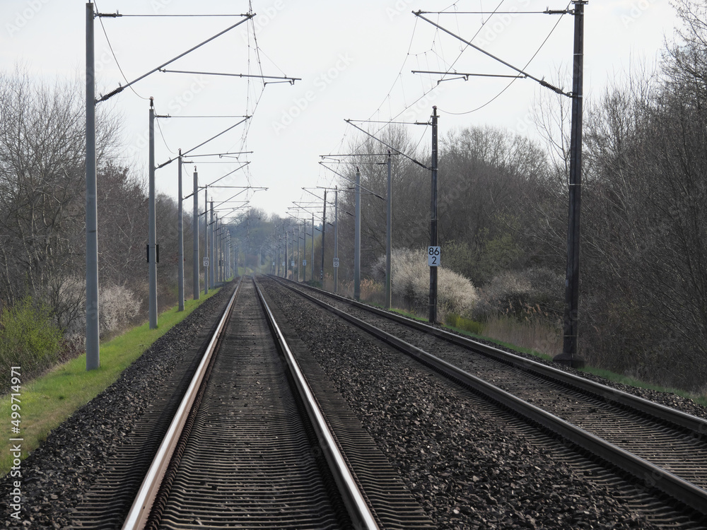 Perspektivische Sicht auf die Gleise der Eisenbahn mit Schienen, Schwellen, Schotter und Oberleitungen