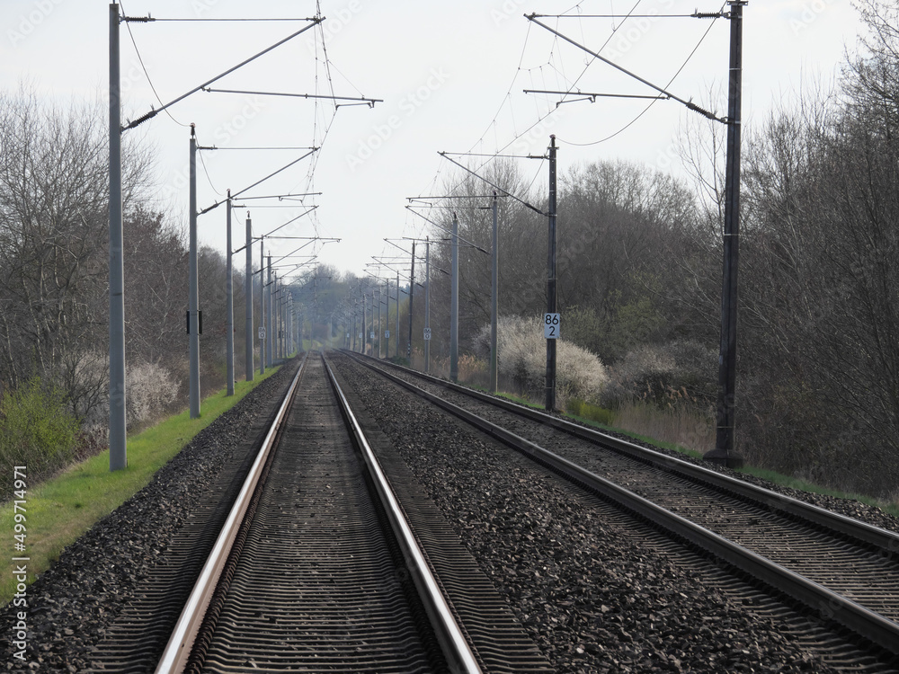 Perspektivische Sicht auf die Gleise der Eisenbahn mit Schienen, Schwellen, Schotter und Oberleitungen Perspektivische Sicht auf die Gleise der Eisenbahn mit Schienen, Schwellen, Schotter und Oberleitungen