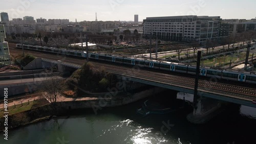 Train crossing Asnieres bridge on Seine river, Paris in France. Aerial panning photo