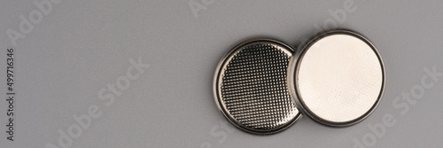 Two round flat batteries on a gray background. Lots of space for text