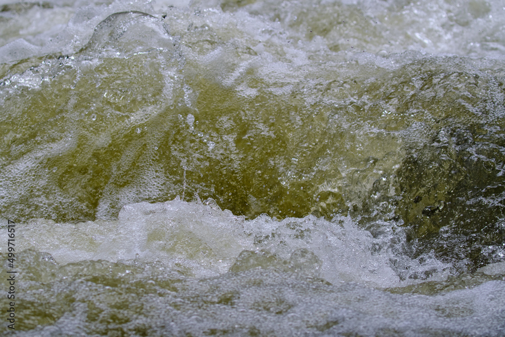 Texture of water in a natural state, in a river when splashing against the stones.