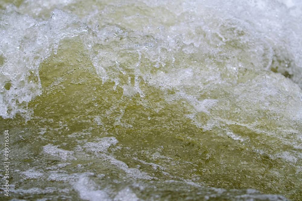 Texture of water in a natural state, in a river when splashing against the stones.
