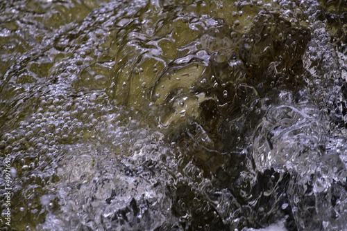 Texture of water in a natural state, in a river when splashing against the stones.