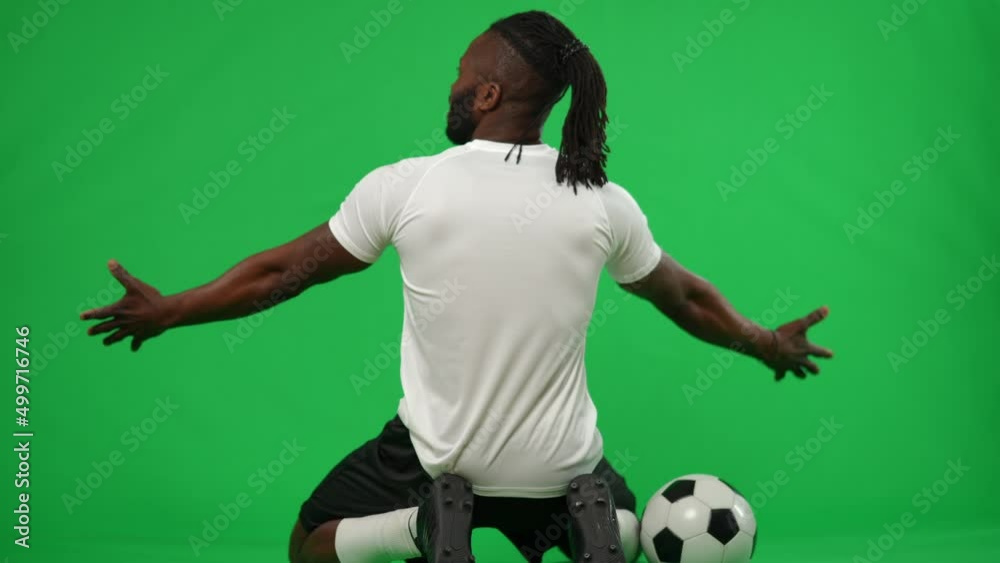 Back view triumphing African American sportsman sitting on knees at chromakey background stretching hands. Successful satisfied footballer rejoicing victory goal on green screen. Template mockup Back view triumphing African American sportsman sitting on knees at chromakey background stretching hands. Successful satisfied footballer rejoicing victory goal on green screen. Template mockup