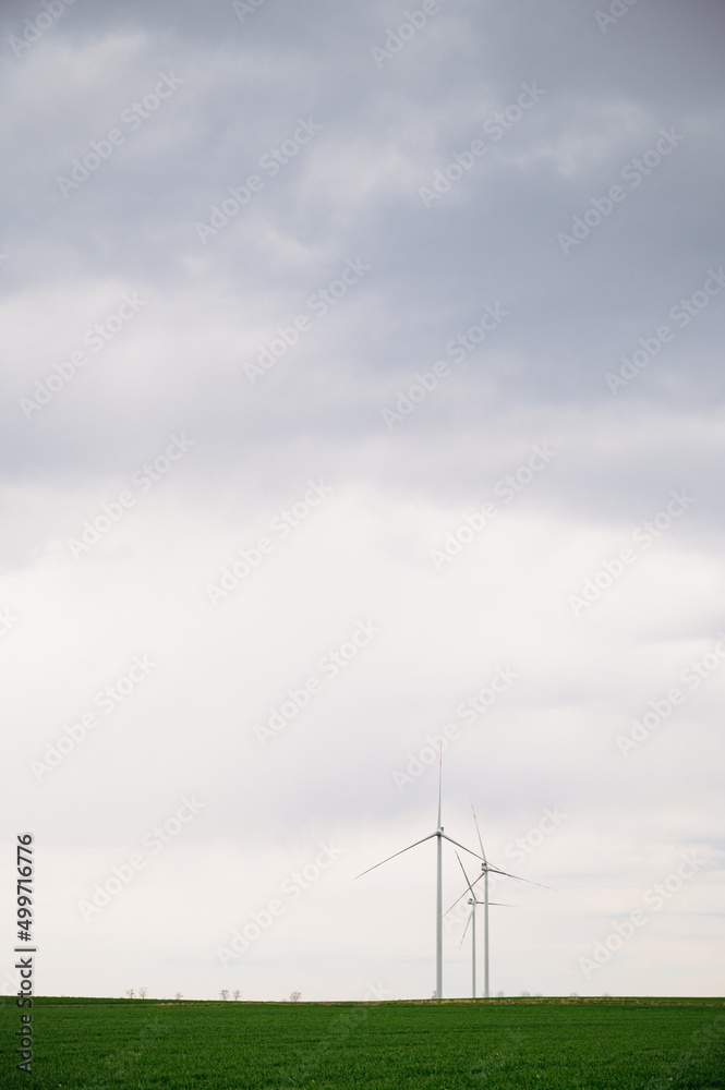 Three wind turbines of a wind farm, producing renewable energy, vertical image. Clean green alternative power. Wind energy to fight climate change and global warming.No fossil fuels or emissions.Earth