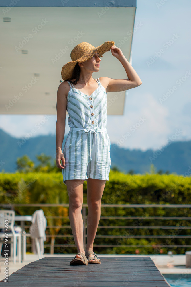 Woman with a straw hat walking on a pool