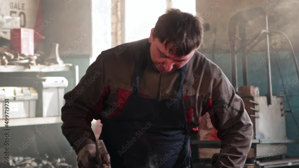 Man blacksmith forming a leaf out of hot piece of metal Man blacksmith forming a leaf out of hot piece of metal