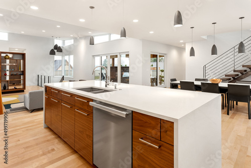 Beautiful open concept kitchen  dining  and living room in new luxury home. Features large quartz waterfall island with sink  dishwasher  elegant cabinets  and drawers.