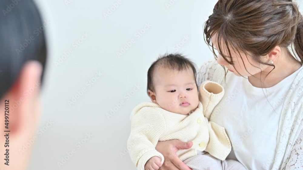 明るいリビングで赤ちゃんを抱っこしあやすお母さん