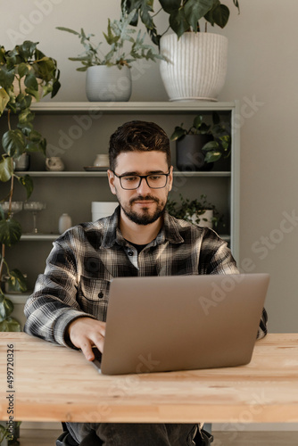 Brunette man in glasses works at home at the computer 