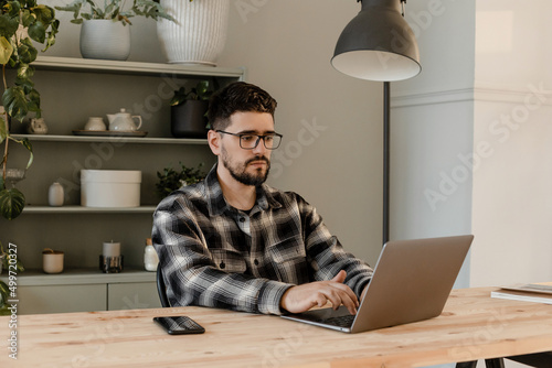Brunette man in glasses works at home at the computer 