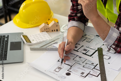 Professional architect working on blueprints and construction plans. Building engineers calculate and draft building construction drawings, civil engineering, and construction business concepts.