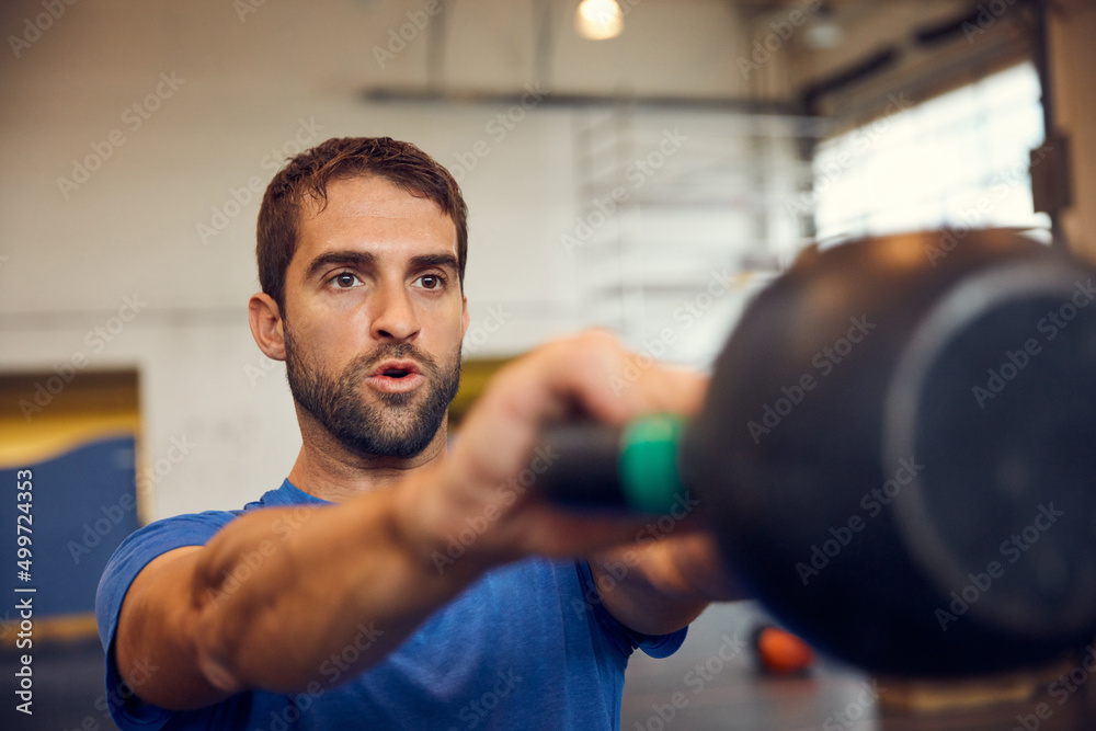 Making great progress towards his goals. Cropped shot of a handsome young man working out with a kettle bell in the gym. Making great progress towards his goals. Cropped shot of a handsome young man working out with a kettle bell in the gym.