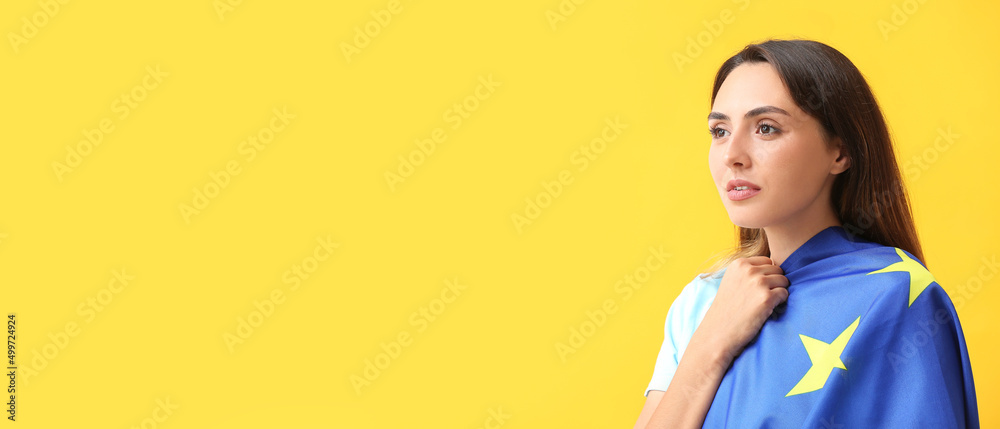 Beautiful young woman with flag of European Union on yellow background with space for text Beautiful young woman with flag of European Union on yellow background with space for text