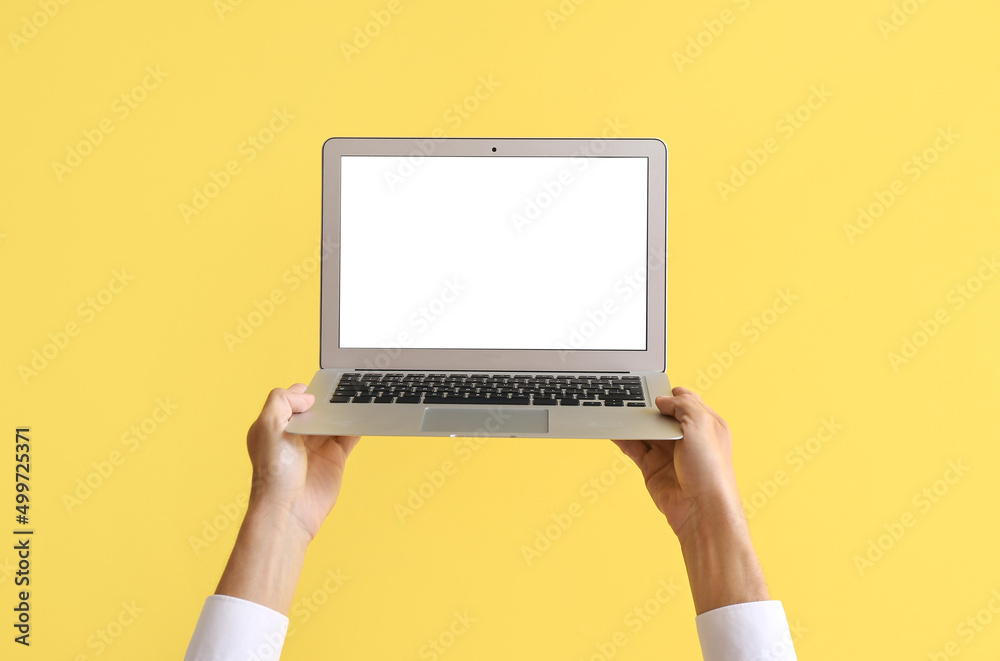 Male hands with modern laptop on color background