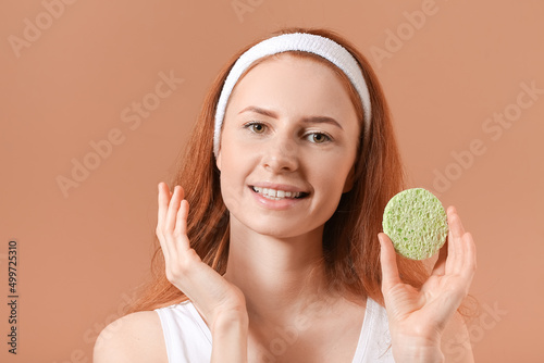 Young woman with makeup sponge on color background photo