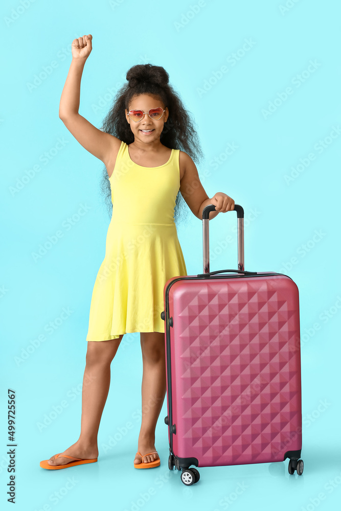 Happy little African-American girl with suitcase on blue background Happy little African-American girl with suitcase on blue background