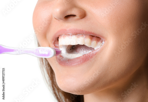 Pretty young woman brushing teeth on white background, closeup