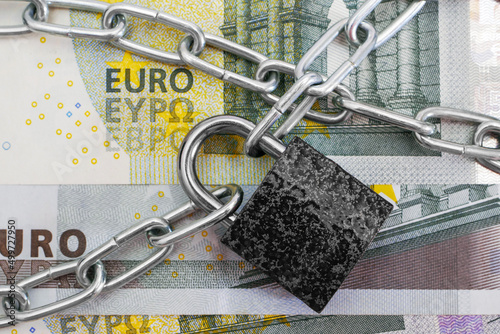 closeup of euro banknote criss-crossed by chain with padlock