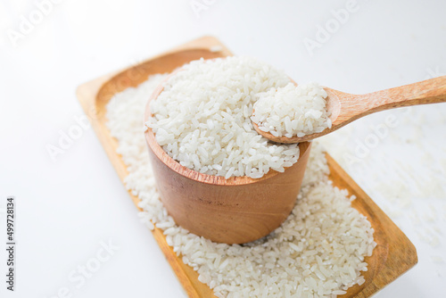 Rice on wooden spoon and wooden bowl